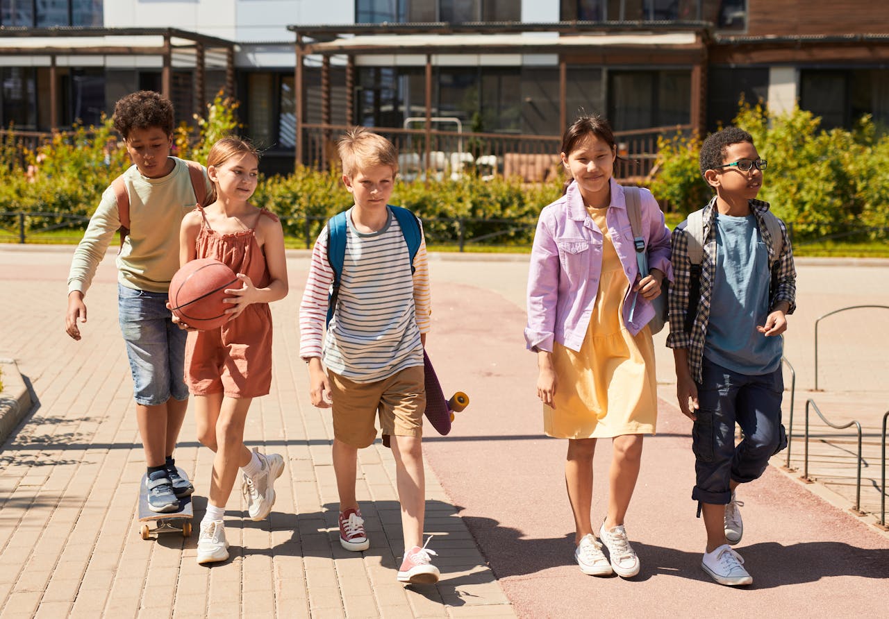 A diverse group of children with backpacks walking together on a sunny day